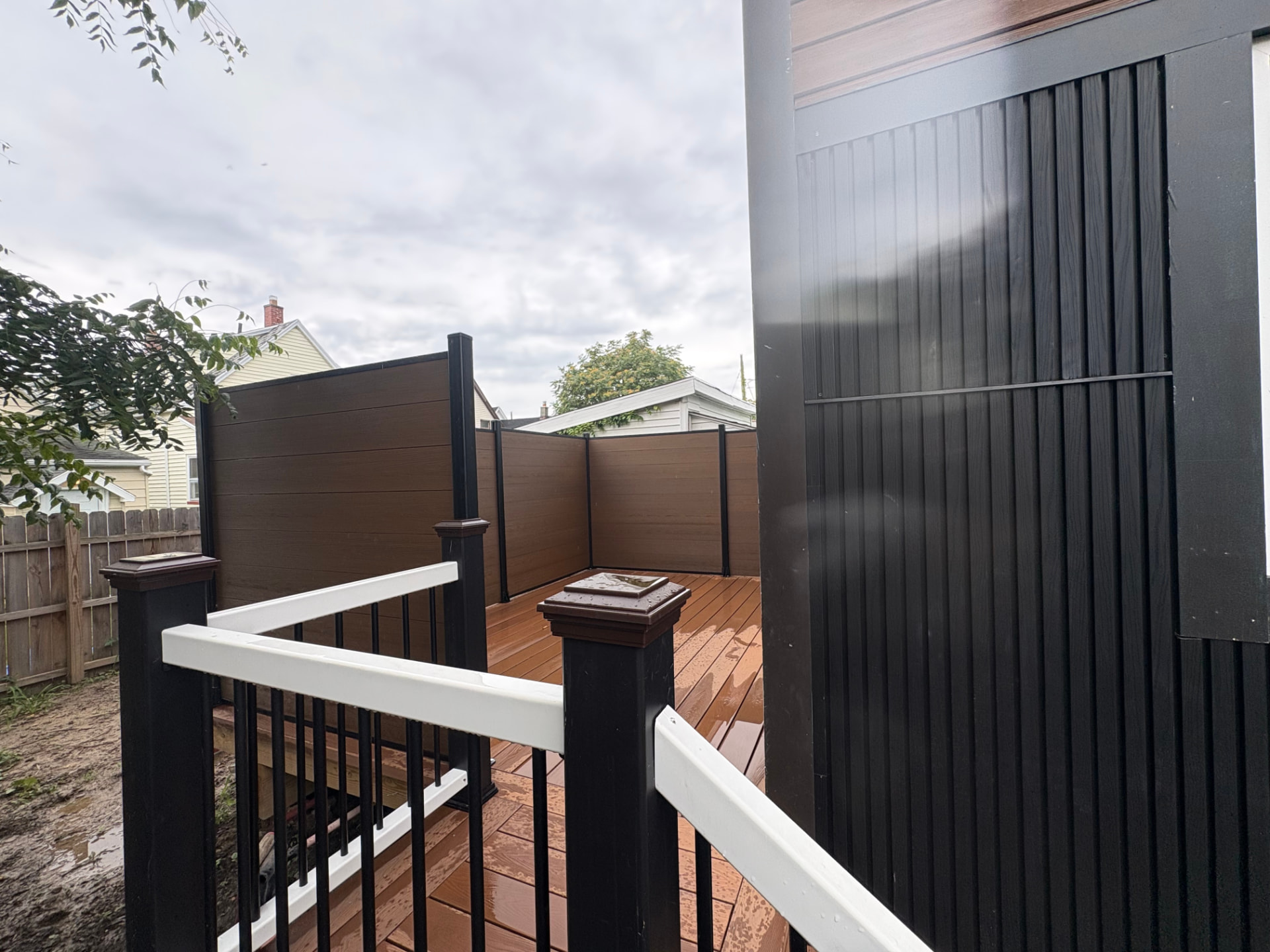 View from deck stairs showing black balusters, white handrail and wood-tone privacy walls